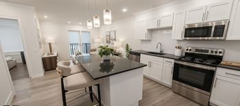 A modern kitchen with a black countertop and stainless steel appliances.